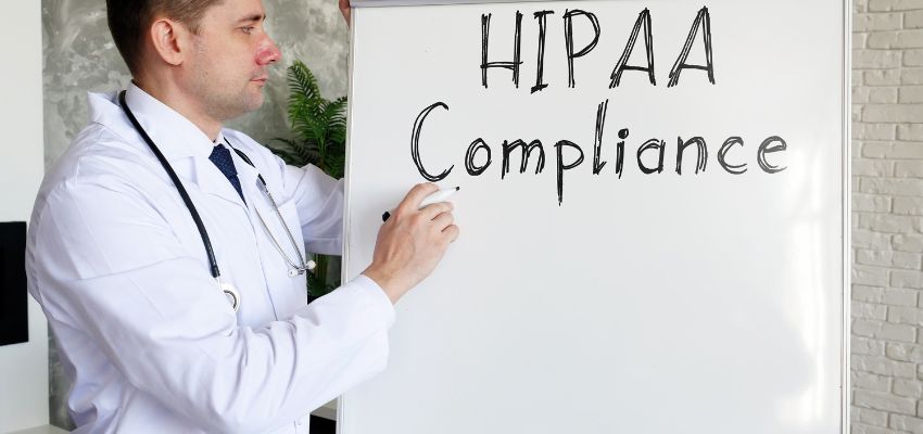 cumplimiento de la hipaa (3) Un médico escribe Cumplimiento de la HIPAA en la pizarra.