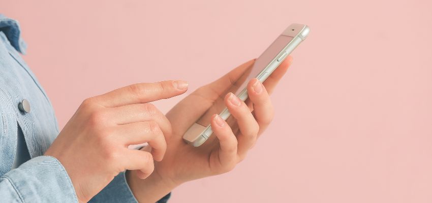Primer plano de una persona con un teléfono móvil utilizando una aplicación de firma para móviles.