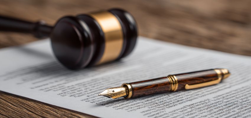 Legal document with gavel and fountain pen illustrating the difference between contract and agreement in law.