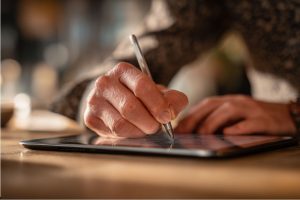 Business professional signing a document on a tablet illustrating duly signed meaning