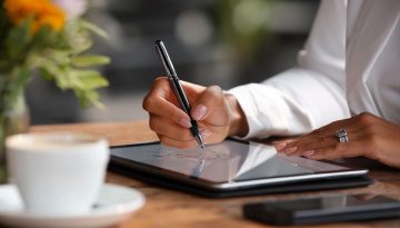 Close-up of a person e-signing a document on a tablet through paperless contract solutions.