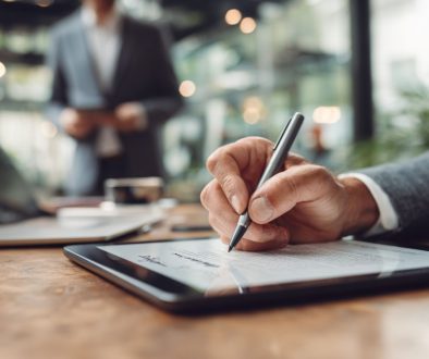 Close-up of a man signing a digital document on a tablet as an authorized signatory.