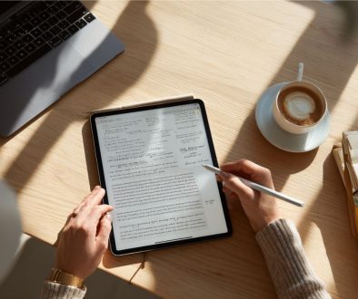 Business professional reviewing digital charts and analytics on a tablet at a sunlit workspace, with coffee and documents nearby, representing the analysis and preparation phase before finalizing a sales contract.