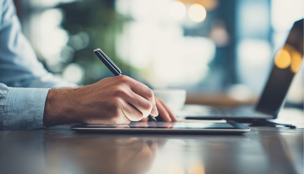 contract-addendum2 A business professional signs a contract addendum on a digital tablet using a stylus at a modern workspace