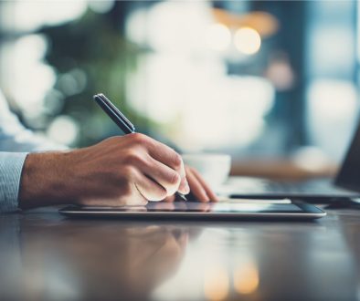A business professional signs a contract addendum on a digital tablet using a stylus at a modern workspace
